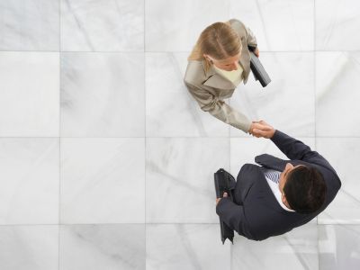Vista dall'alto di uomo d'affari e una donna che si stringono la mano nella hall di un ufficio.