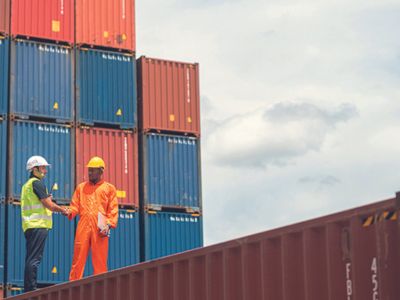 Un ingegnere e un operaio si stringono la mano in un deposito container