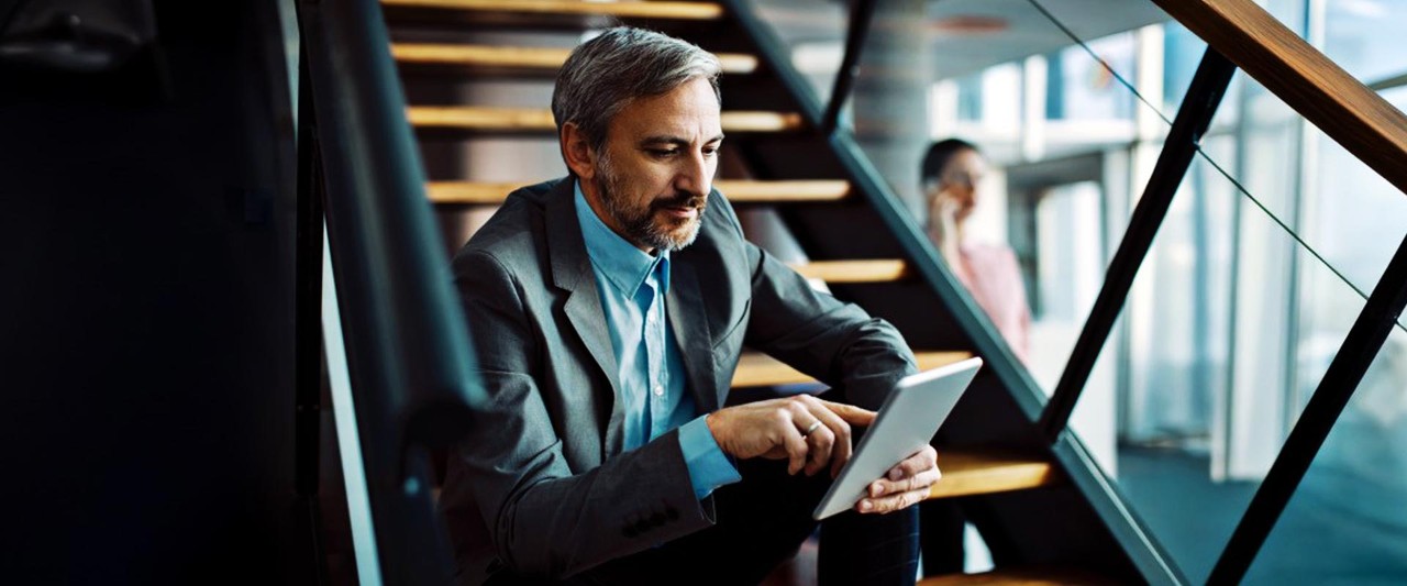 Businessman sitting on stairs with tablet