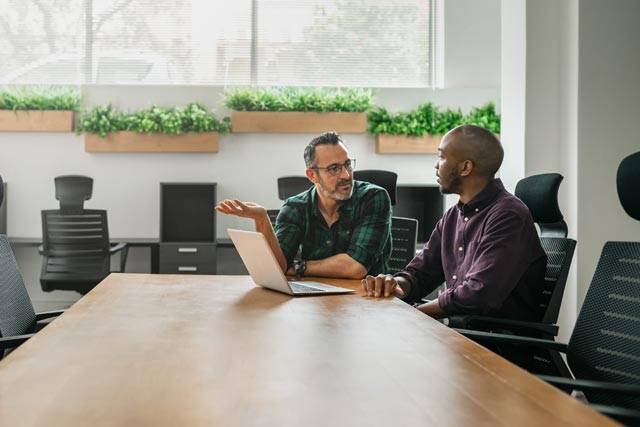 two man in front of the laptom in the office