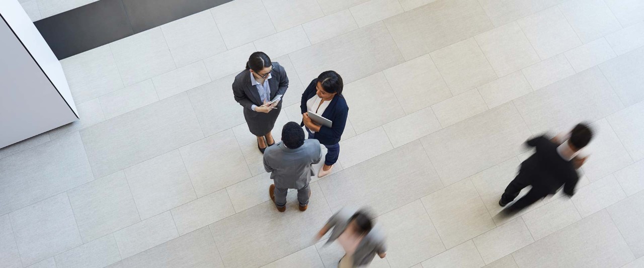 Directly above view of business colleagues in formalwear standing in lobby of company