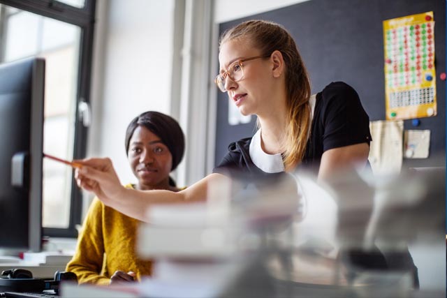 two woman in fornt of desktop