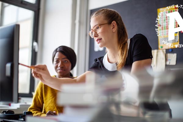 two businesswomen at an office desk in a meeting