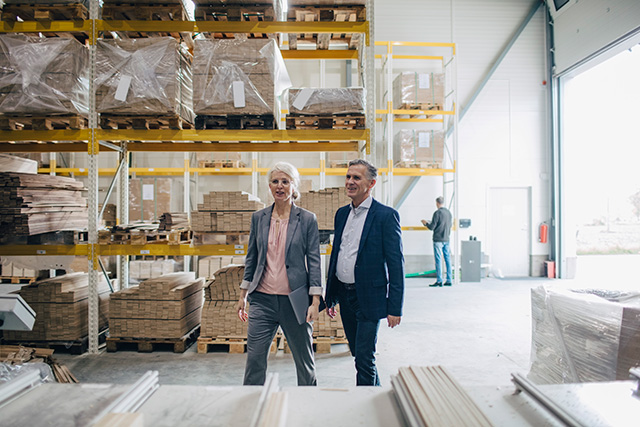 A man and a woman are walking and chatting in the warehouse.