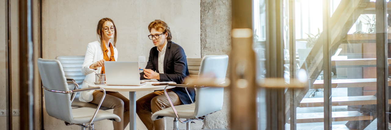 young man and woman in office setting looking at computer