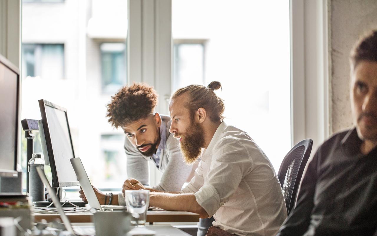 2 co-workers looking intently at computer