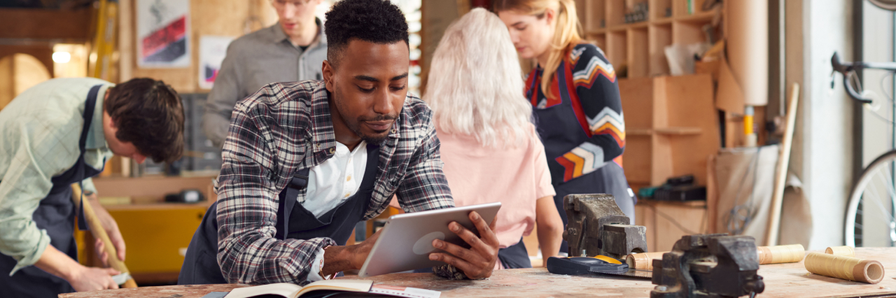 man leaning forward on table and looking at tablet