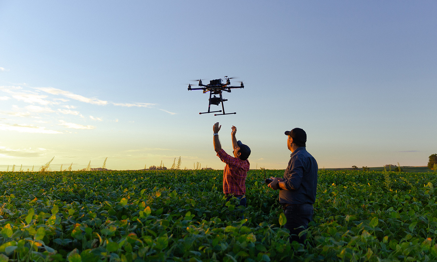 two men launching drone in farm field