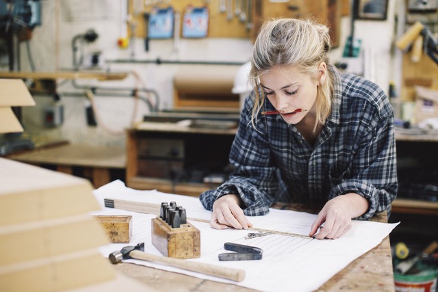 woman leaning over table with pencil in mouth