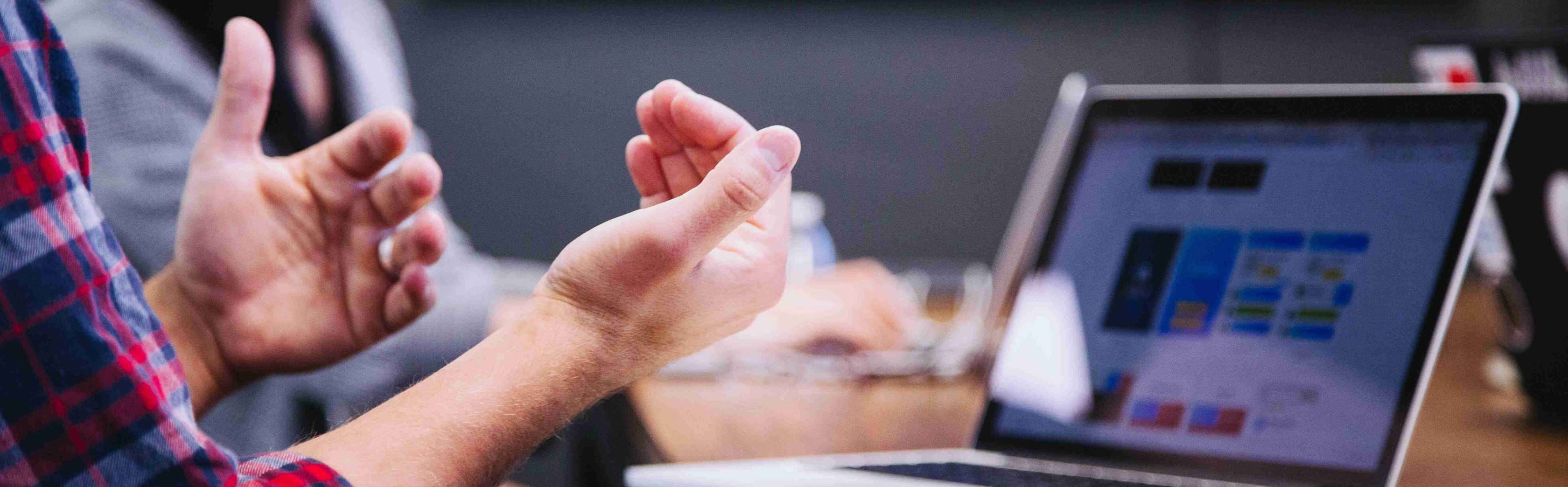 a man's hands waiving in front of a laptop