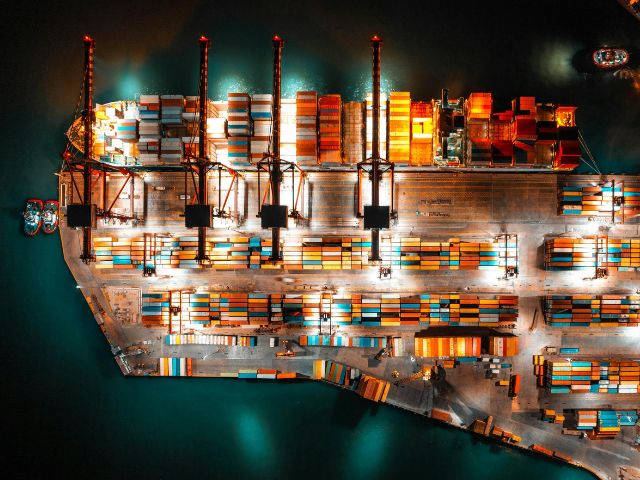 Molo di un porto commerciale con container di merci visto dall'alto, di notte