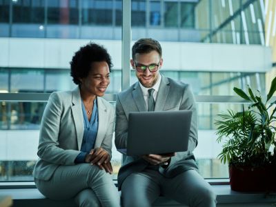 Due persone che guardano lo schemo del computer e sorridono