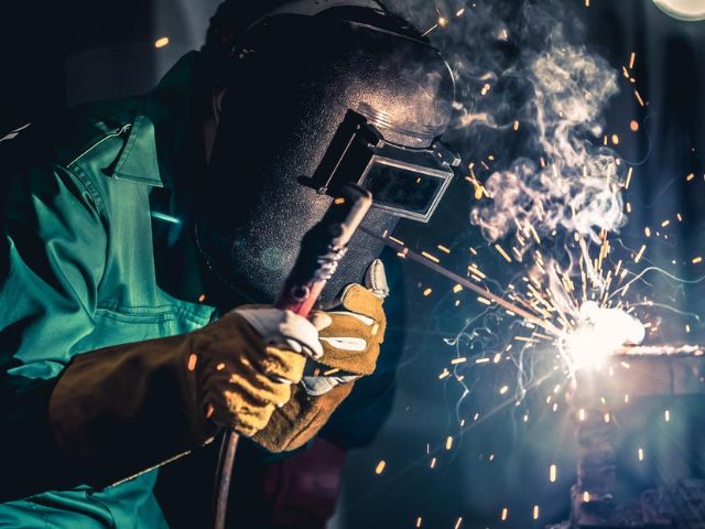 Un saldatore a lavoro con indosso una maschera protettiva