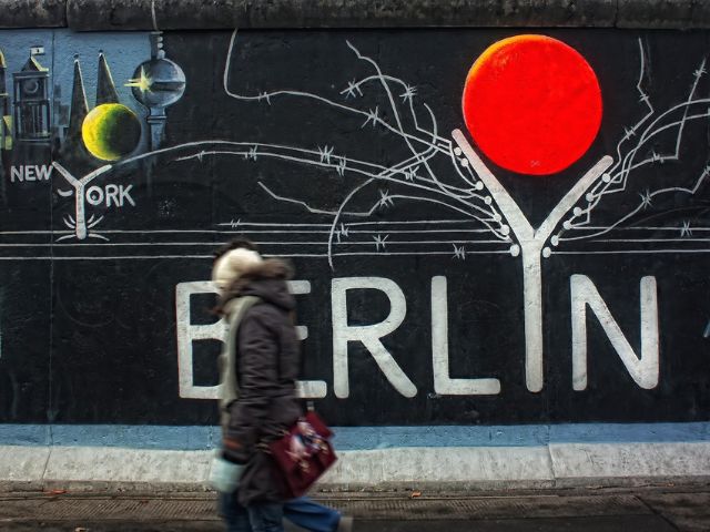 Una donna passa davanti ad un murales a Berlino