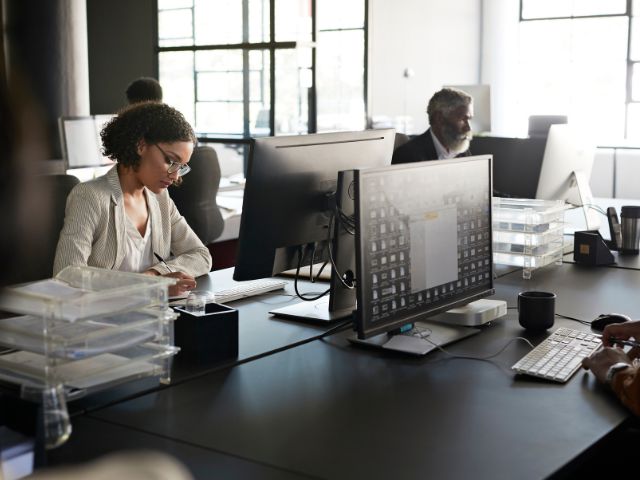 Colleghi lavorano in un ufficio con scrivanie nere