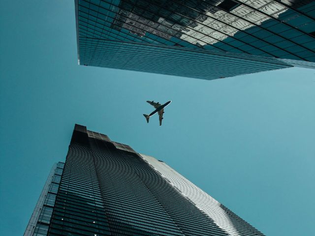 Vista dal basso di un aereo che vola sopra due grattacieli