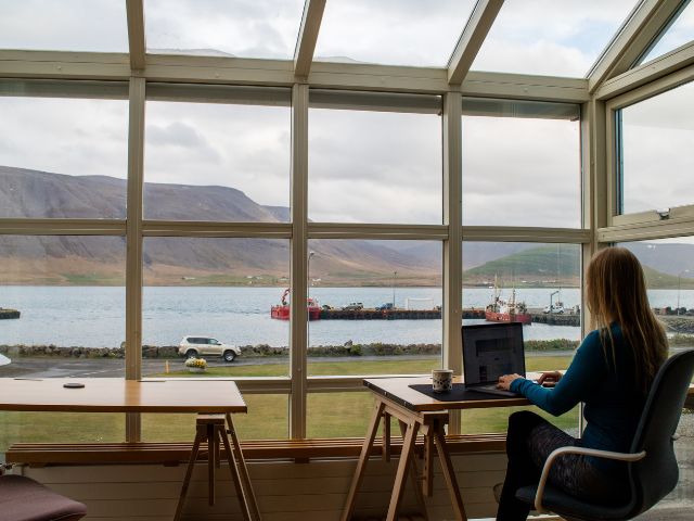 Un'imprenditrice lavora usando il laptop in un café con vista su un lago