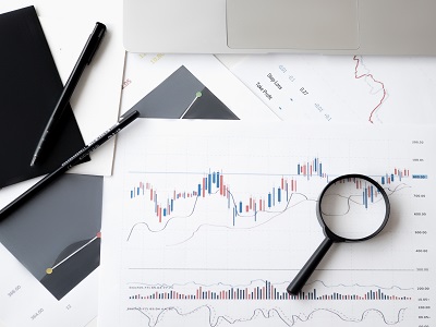 Penne, lente d'ingrandimento e documenti con grafici su una scrivania