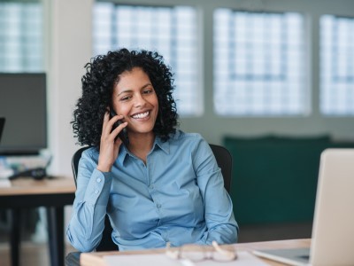 Una manager seduta alla sua scrivania è al telefono con un collega