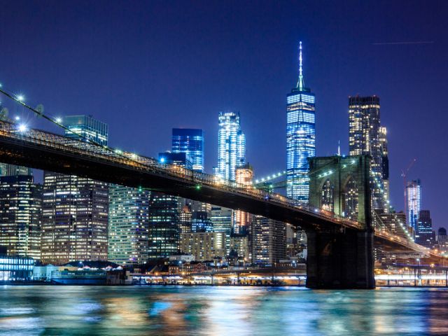 Vista di un ponte e dello skyline di New York di sera