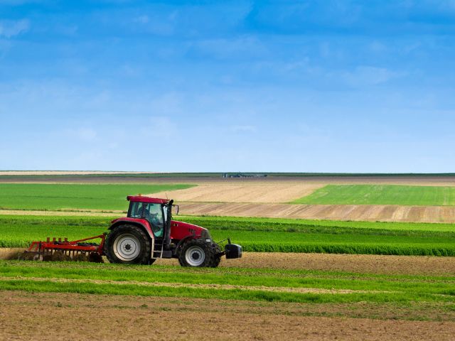 Un trattore rosso ara un campo