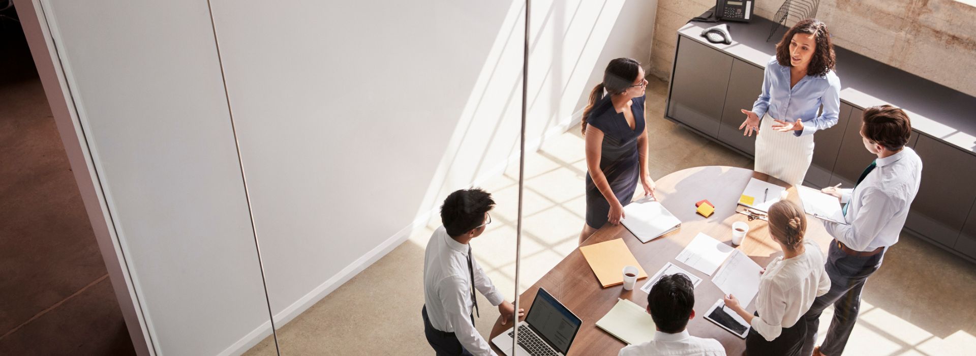 Colleghi in piedi attorno a un tavolo in sala riunioni