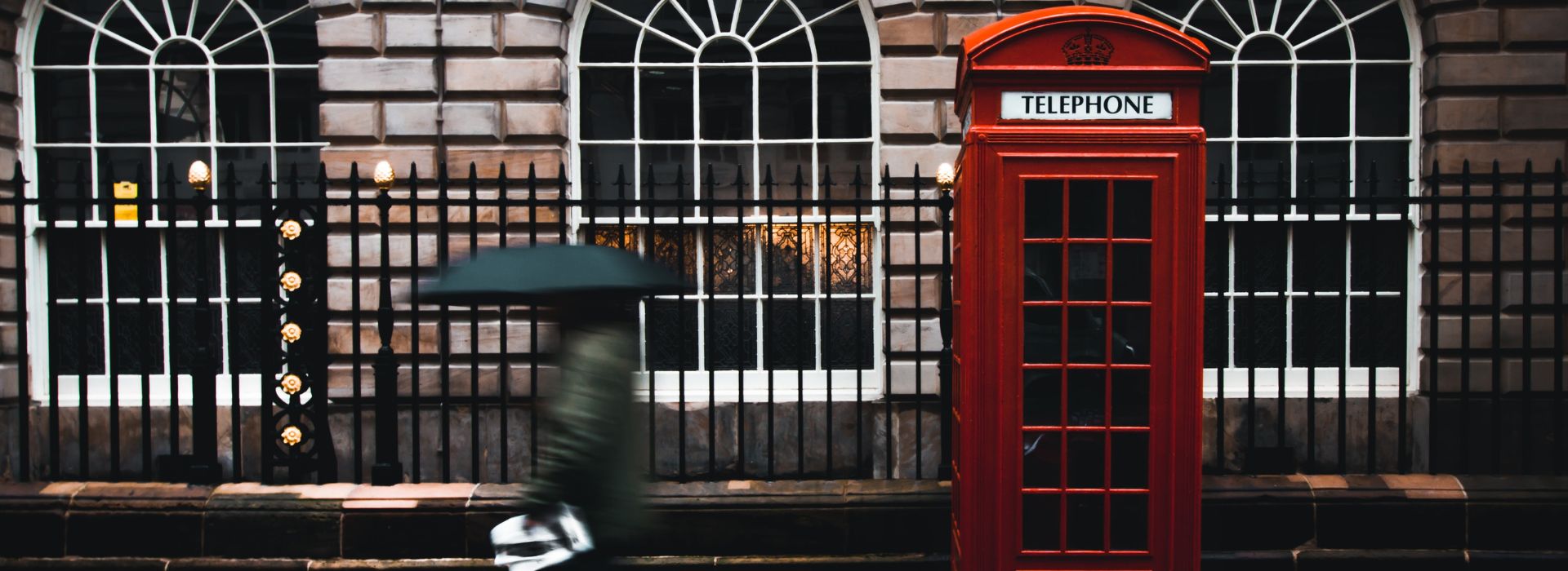 Strada di Londra con cabina telefonica e persona che cammina con l'ombrello aperto