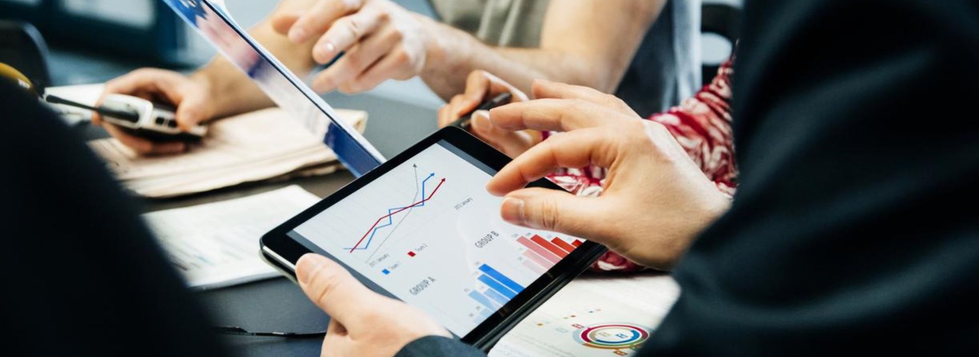 Dei colleghi confrontano i dati utilizzando documenti e un tablet durante una riunione