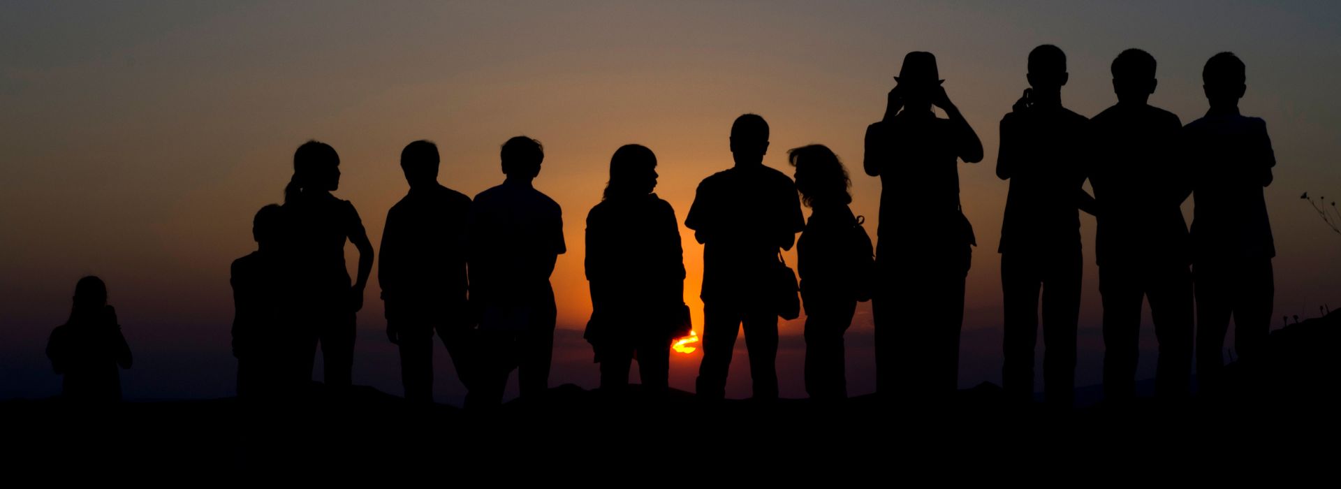 Delle persone di spalle ammirano un tramonto
