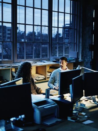 frau und mann in einem dunklen büro am computer