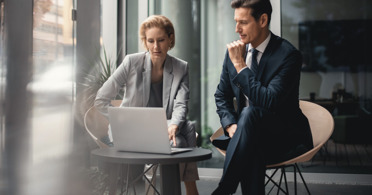 Deux personnes qui discutent autour d'une table, face à un ordinateur